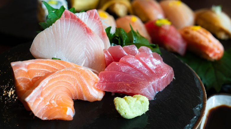 plate of sashimi with sushi in background