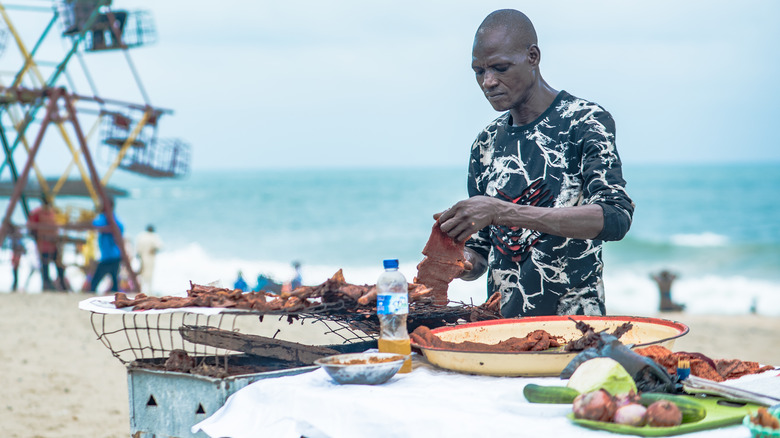 A man on a beach in Lagos preparing suya