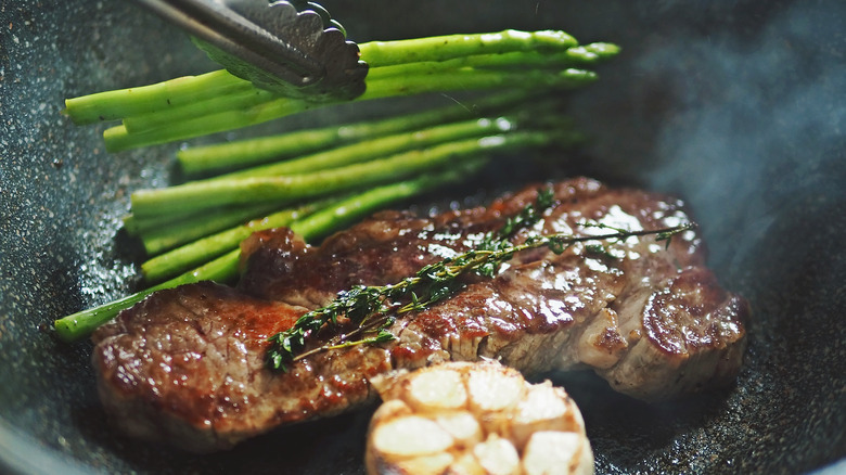 steak and asparagus in skillet