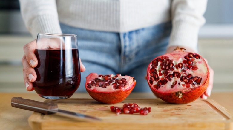 Pomegranate juice in glass next to pomegranates