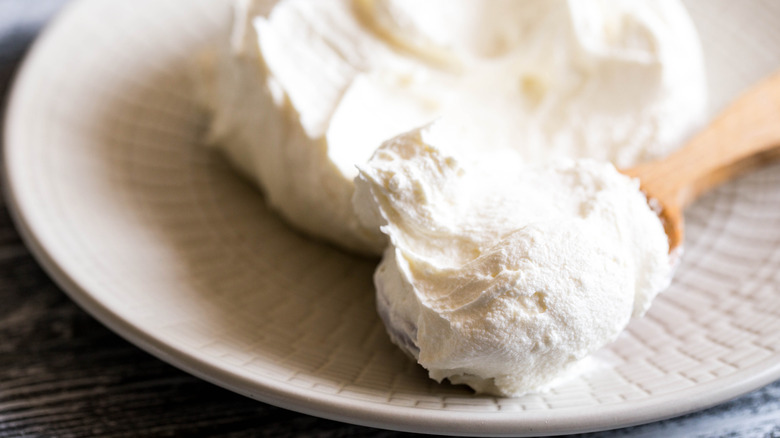 fresh mascarpone on a white plate with a wooden spoon