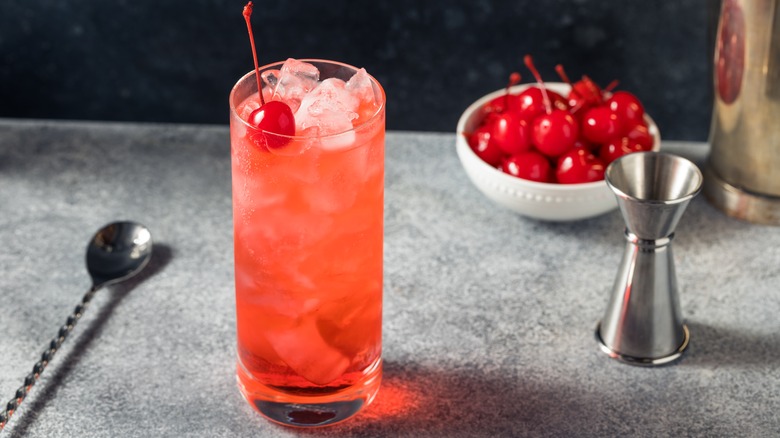 Dirty Shirley cocktail beside a bowl of maraschino cherries