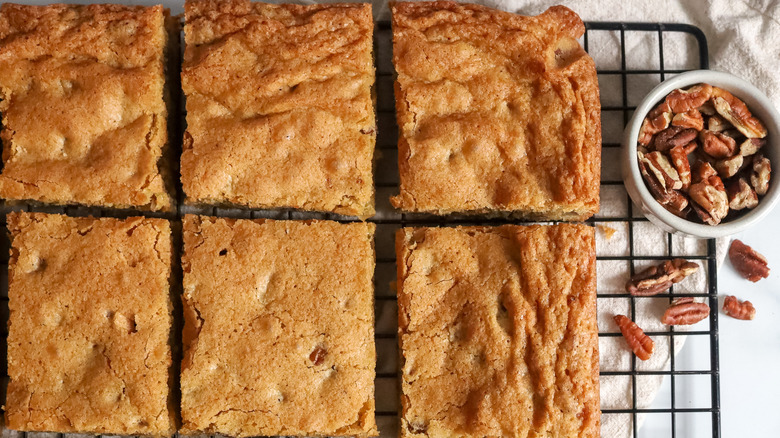light brown bread, cake, or bar cookies on a wire rack next to a bowl of pecans