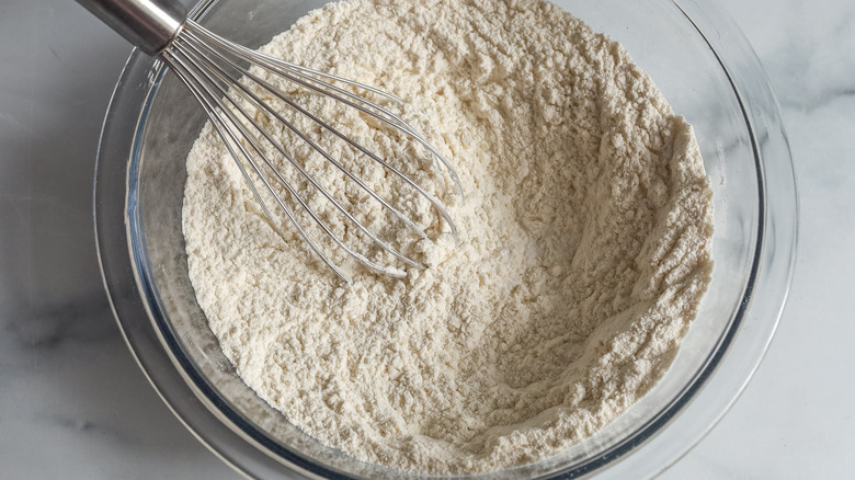flour in a clear bowl with a wire whisk