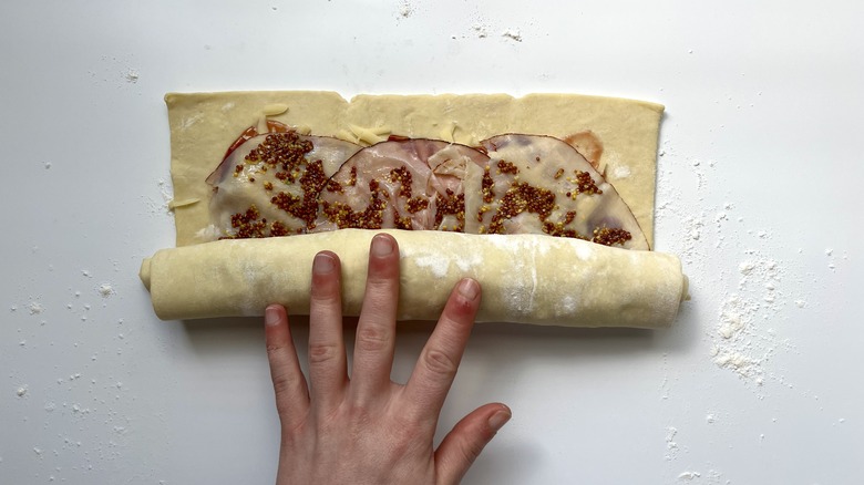 hand rolling puff pastry into a log