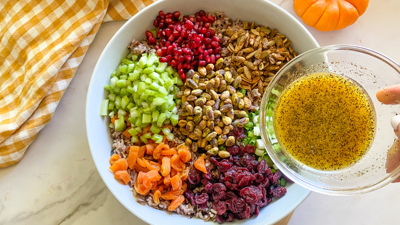 Hand adding dressing to bowl of ingredients