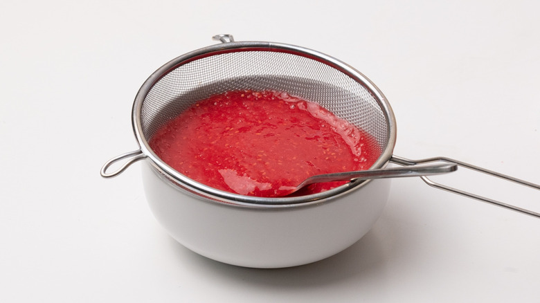 sieving raspberry sauce