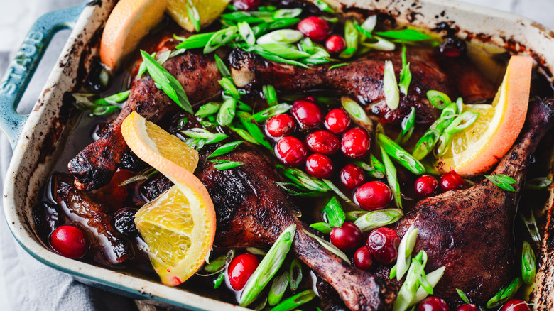 Duck legs, cranberries and orange in casserole dish