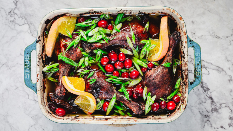 Duck legs, cranberries and orange in casserole dish