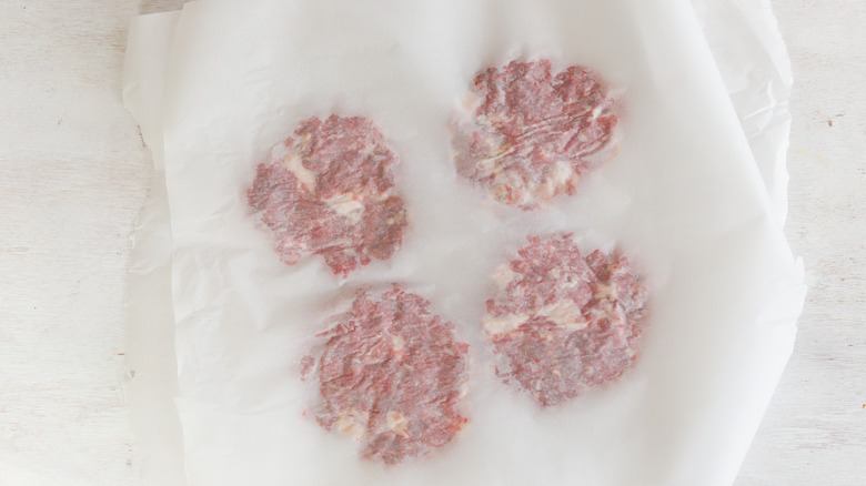 burger patties smashed between parchment paper