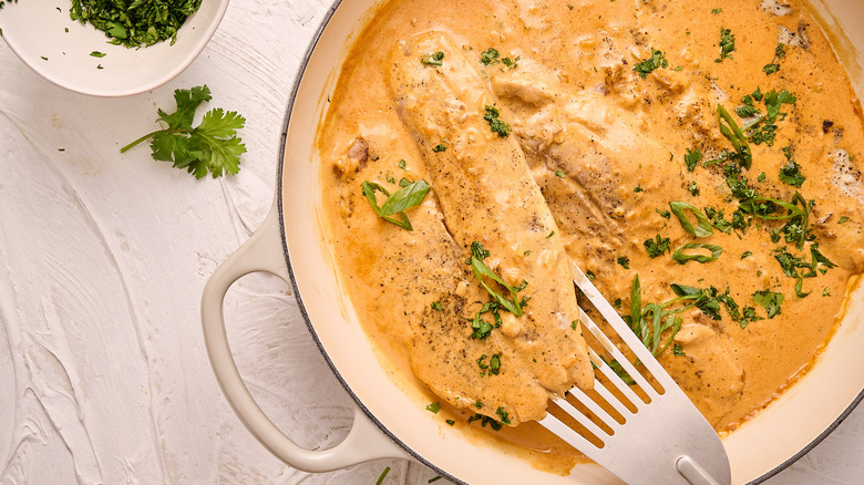 tilapia in skillet with sauce