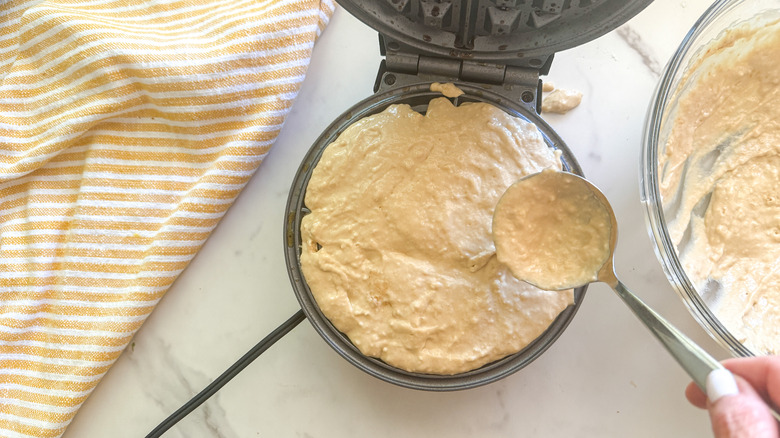 hand adding batter to waffle maker