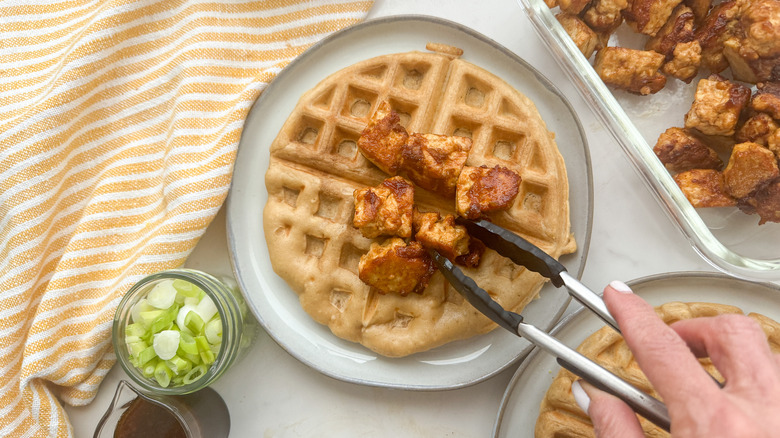 hand adding tofu to waffle