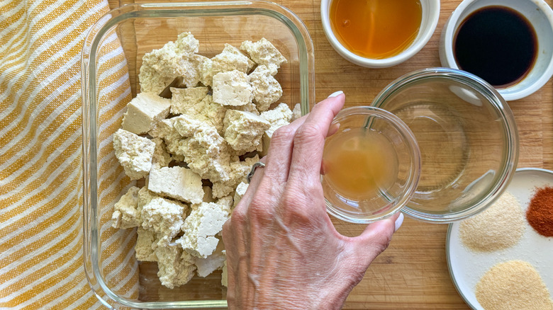 hand adding liquid to bowl