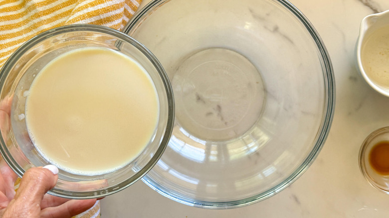 hand adding milk to bowl