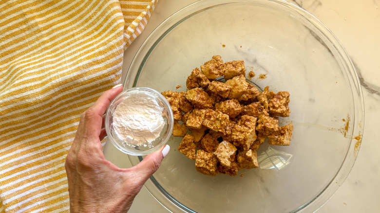 hand adding cornstarch to bowl