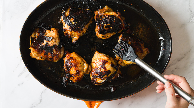 Brushing Chicken in cast iron pan with marinade