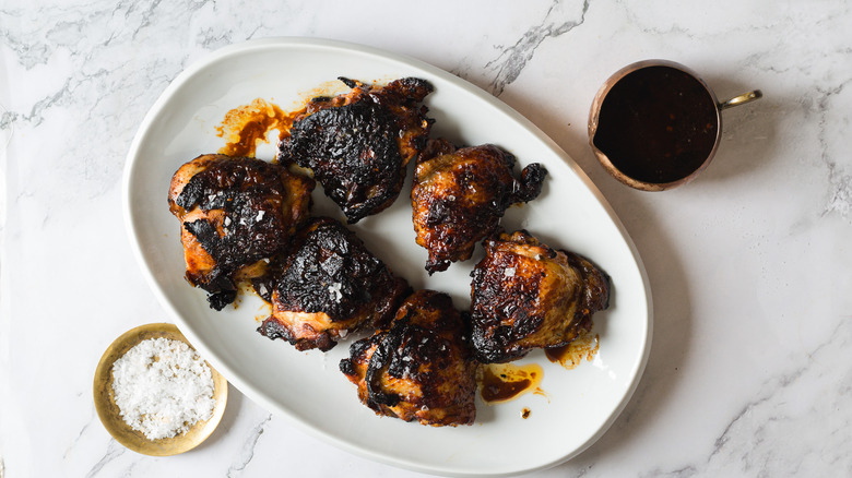 Chicken on white platter with glaze and salt besides