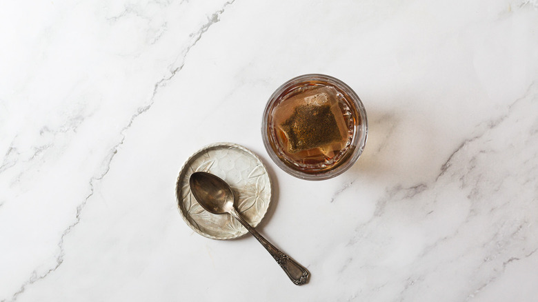 Tea in cup with water beside spoon