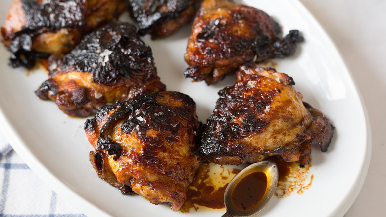 Close up on chicken on white platter with sauce in spoon