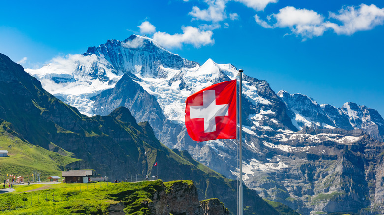 Swiss flag waving near mountains 