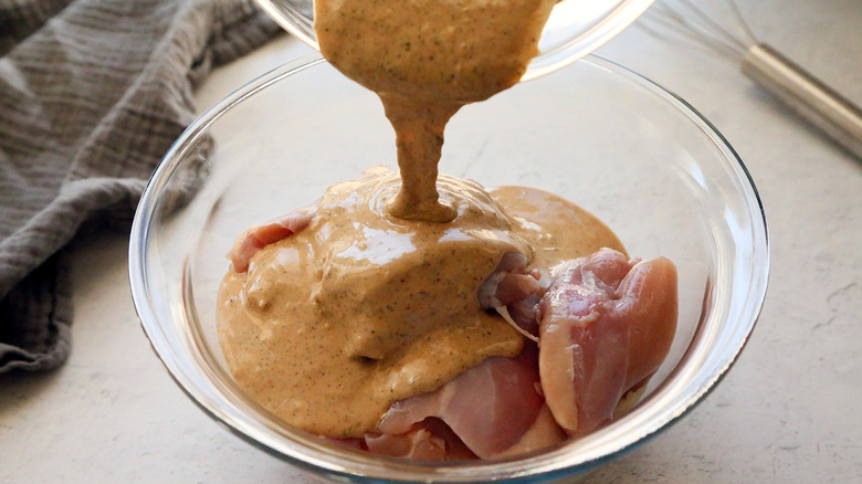 pouring tahini marinade over chicken