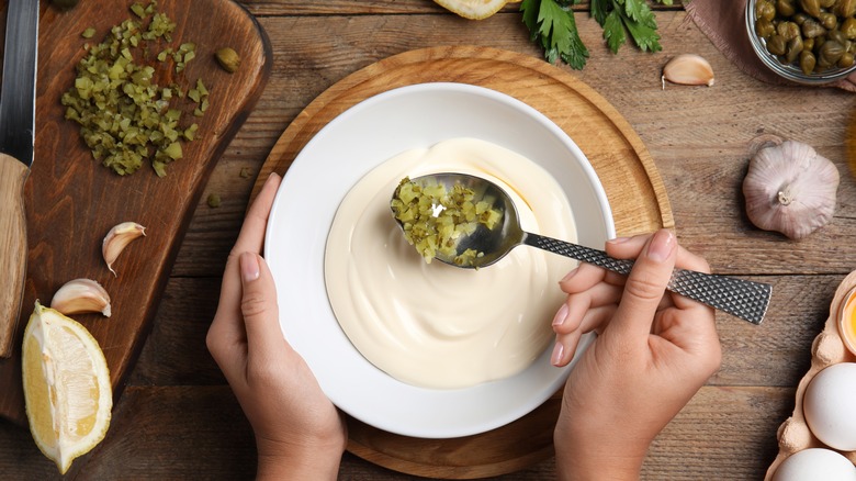 Mixing pickles into tartar sauce