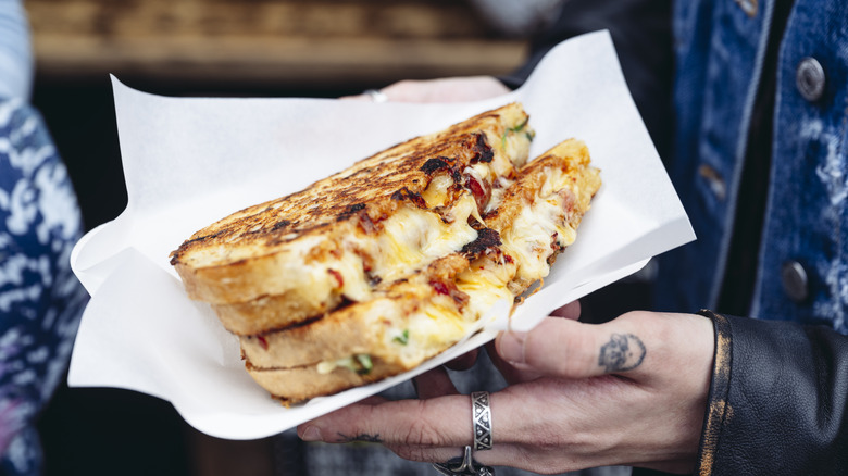 Person holding a grilled cheese sandwich with fillings