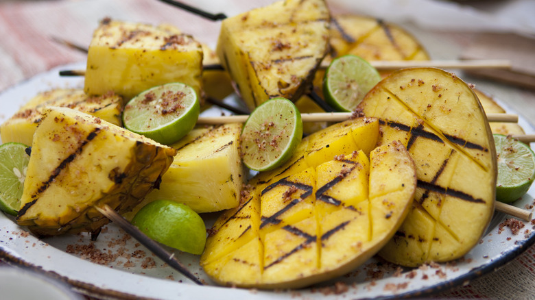 Grilled pineapples, mangos, and limes on a plate