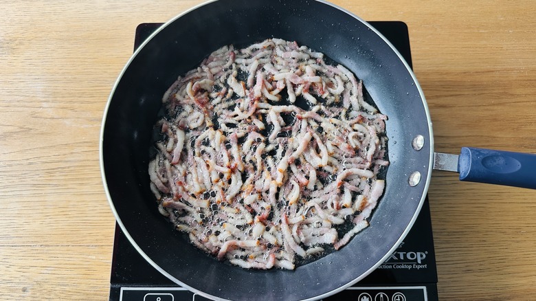 bacon pieces frying in skillet