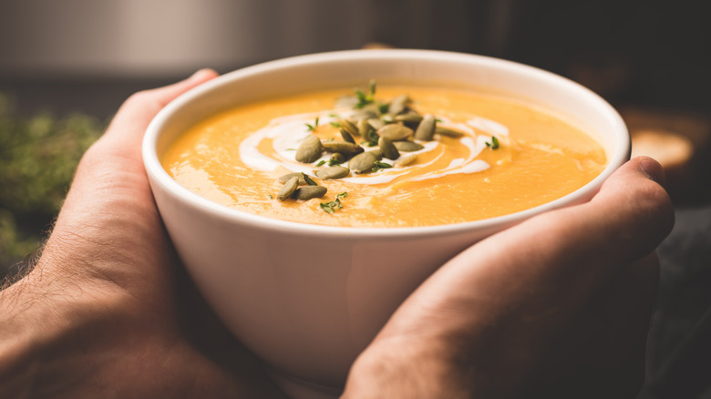 warming hands on pumpkin soup