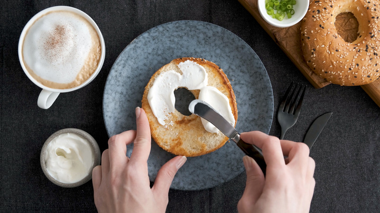 Person spreading cream cheese on a bagel