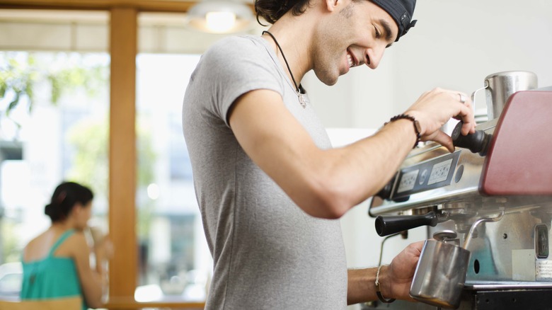 Smiling barista using espresso machine