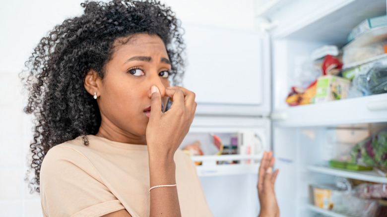 woman disgusted by something in fridge