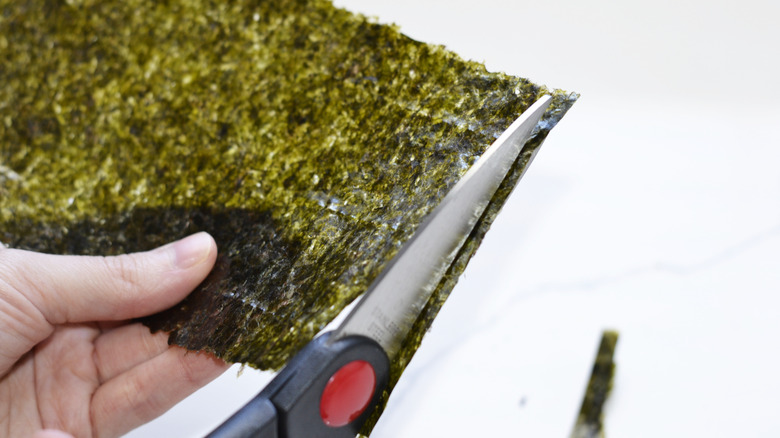 Scissors cutting a sheet of nori into strips