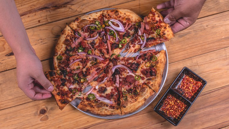 hands grabbing pizza on table