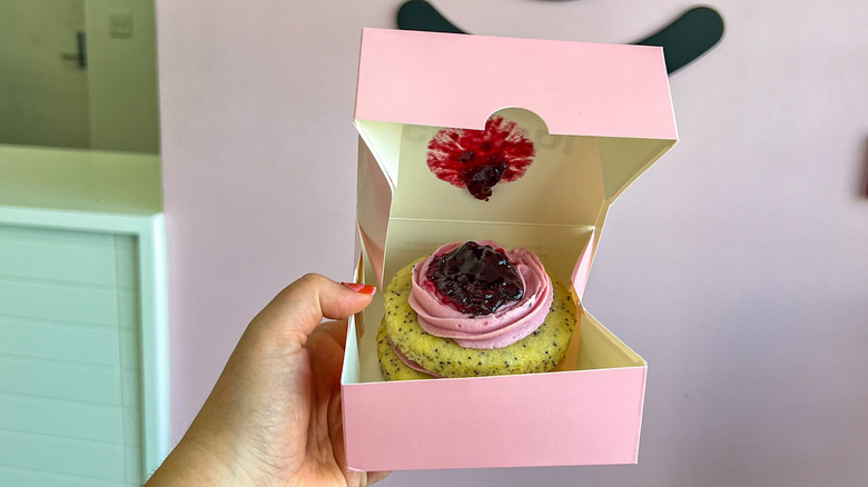 Hand holding pink crumbl cake box