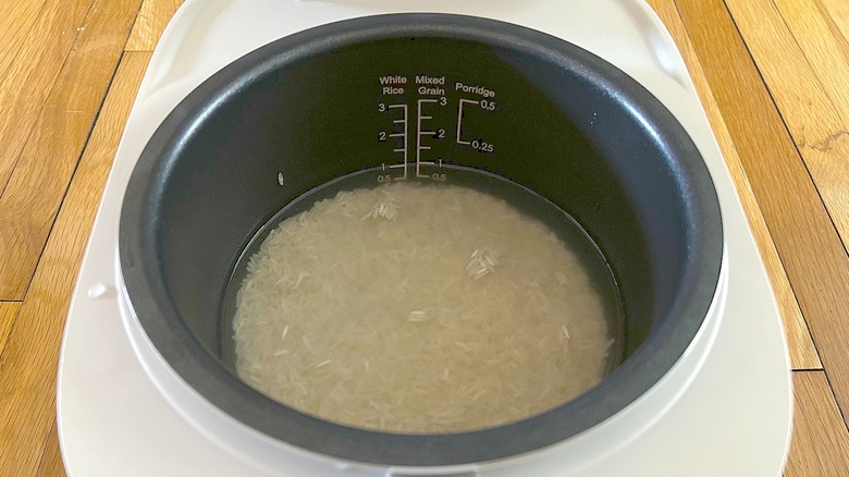 Uncooked rice and water in cooking pot of Toshiba Mini Rice Cooker