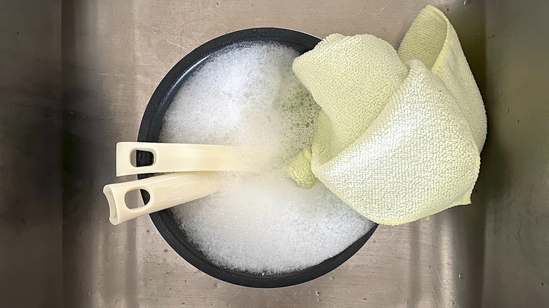 Cooking pot and utensils of Toshiba Mini Rice Cooker in sink with soapy water and cloth