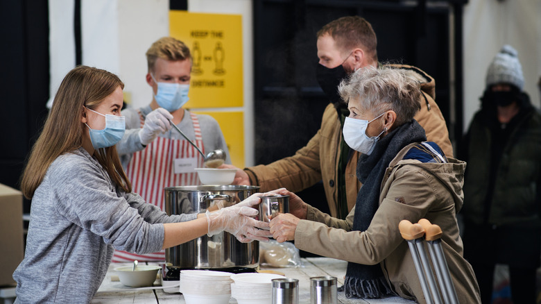 Volunteers handing out hot soup at a food kitchen