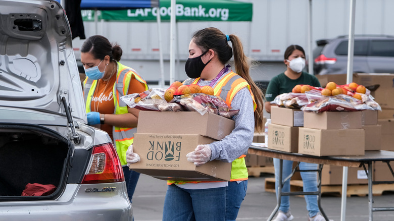 Volunteers at a food bank carrying boxes of produce