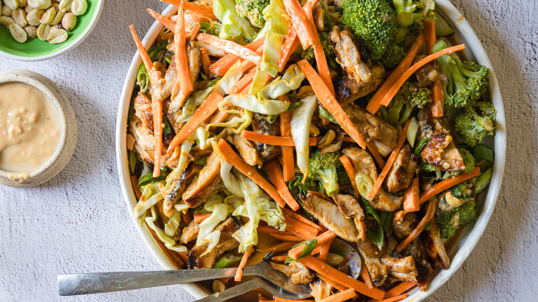 Salad on large white platter with sauce and peanuts on the side