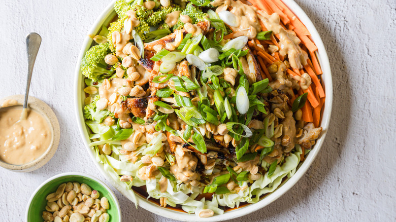 Salad on large white platter with sauce and peanuts on the side