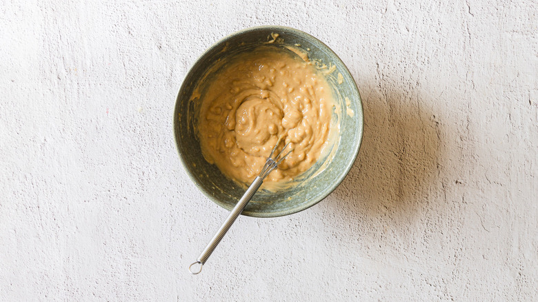 Peanut sauce in blue bowl with whisk