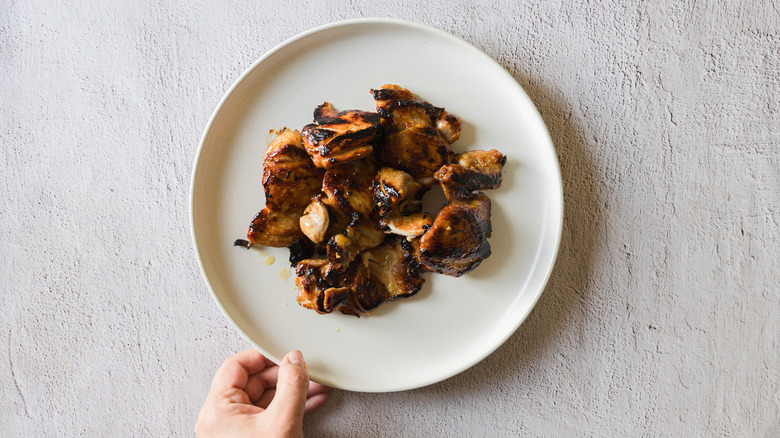 Hand holding chicken on a plate