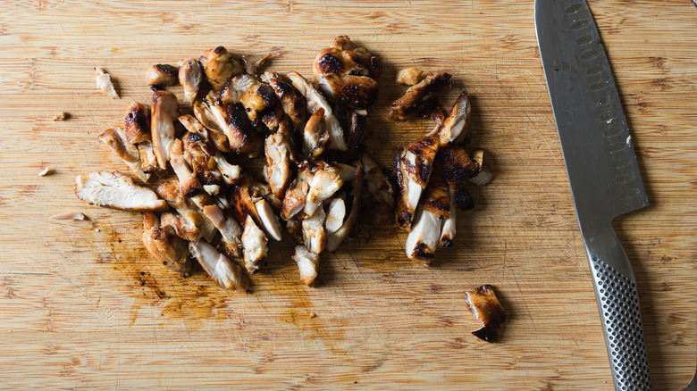 Sliced chicken and knife on cutting board