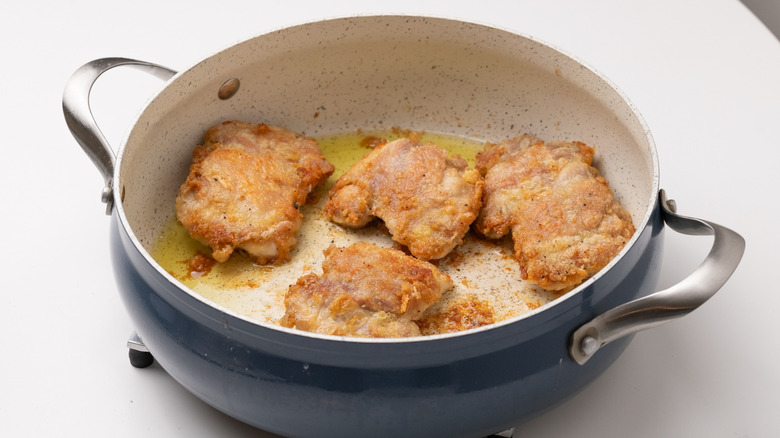 Chicken thighs frying in pan