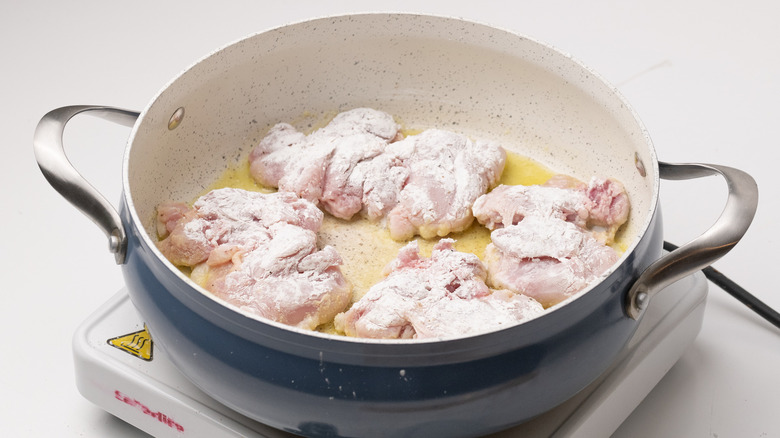 chicken thighs frying in pan