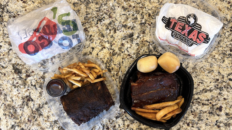 Chili's and Texas Roadhouse baby back ribs with fries in to-go containers on marble countertop