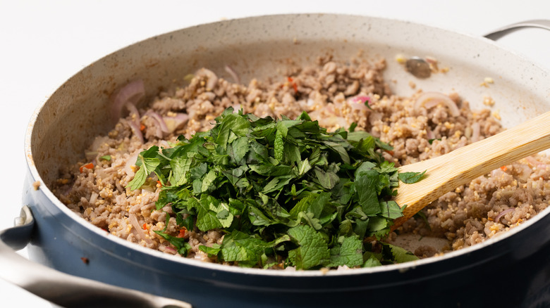 Adding chopped herbs to mince